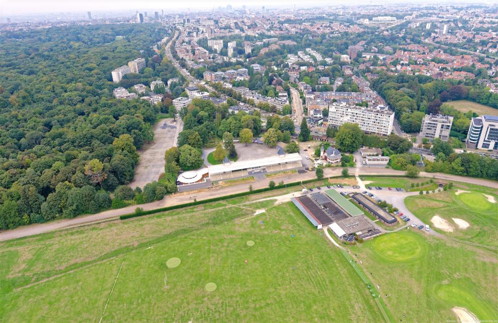 Luchtfoto van de hippodroom vanuit het Zoniënwoud, met de eerste stadswijken op de achtergrond.